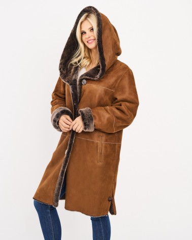Modelka prezentuje długi kożuch damski z kapturem i guzikami, stylizacja na zimę.