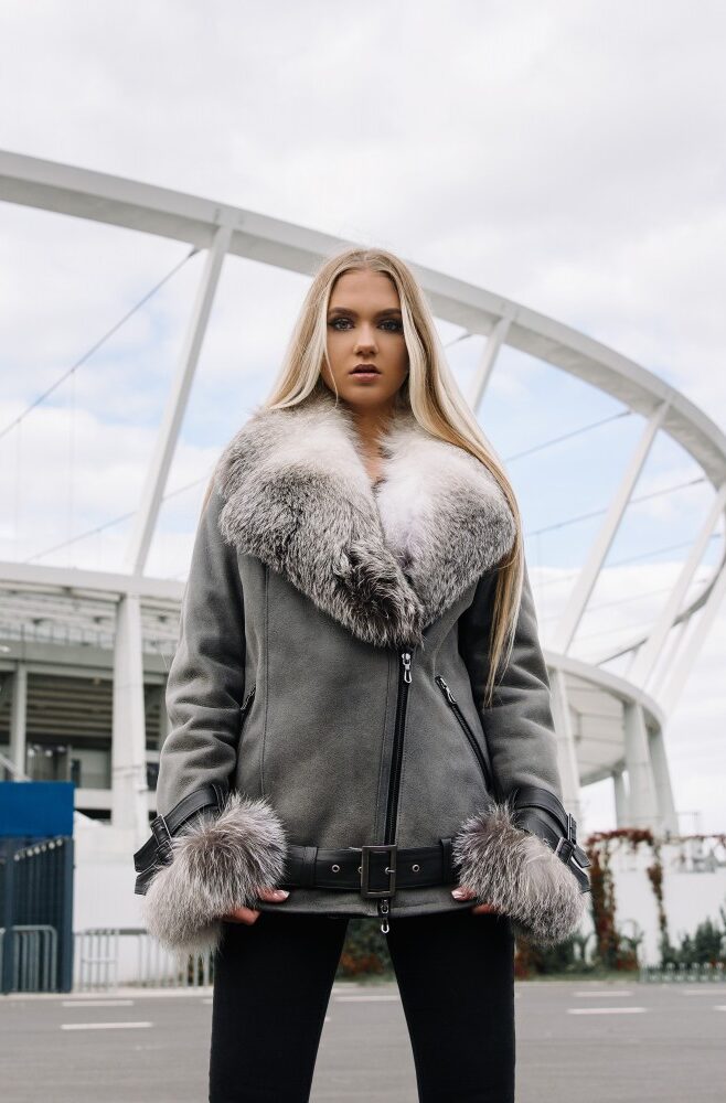 Kożuch damski w szarym kolorze z futrzanym kołnierzem i mankietami, zapinany na zamek z paskiem w talii