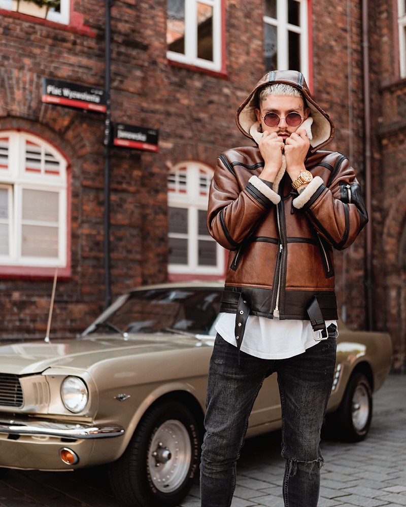 Kożuch męski w brązowym kolorze z kapturem, ozdobiony podszewką z futra i metalowymi detalami