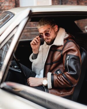 Męski kożuch w brązowym kolorze z białym futrem, z zamkami i stylowym krojem, idealny na zimowe dni