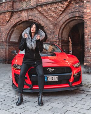 Czarny kożuch damski z futrzanym kołnierzem, idealny na zimowe dni, stylowy i elegancki w połączeniu z czarnymi spodniami