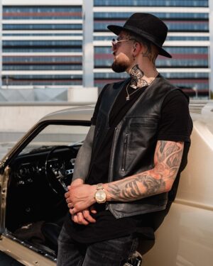 Kamizelka skórzana męska w kolorze czarnym z kieszeniami, noszona na czarnym t-shircie z tatuażami na ramionach