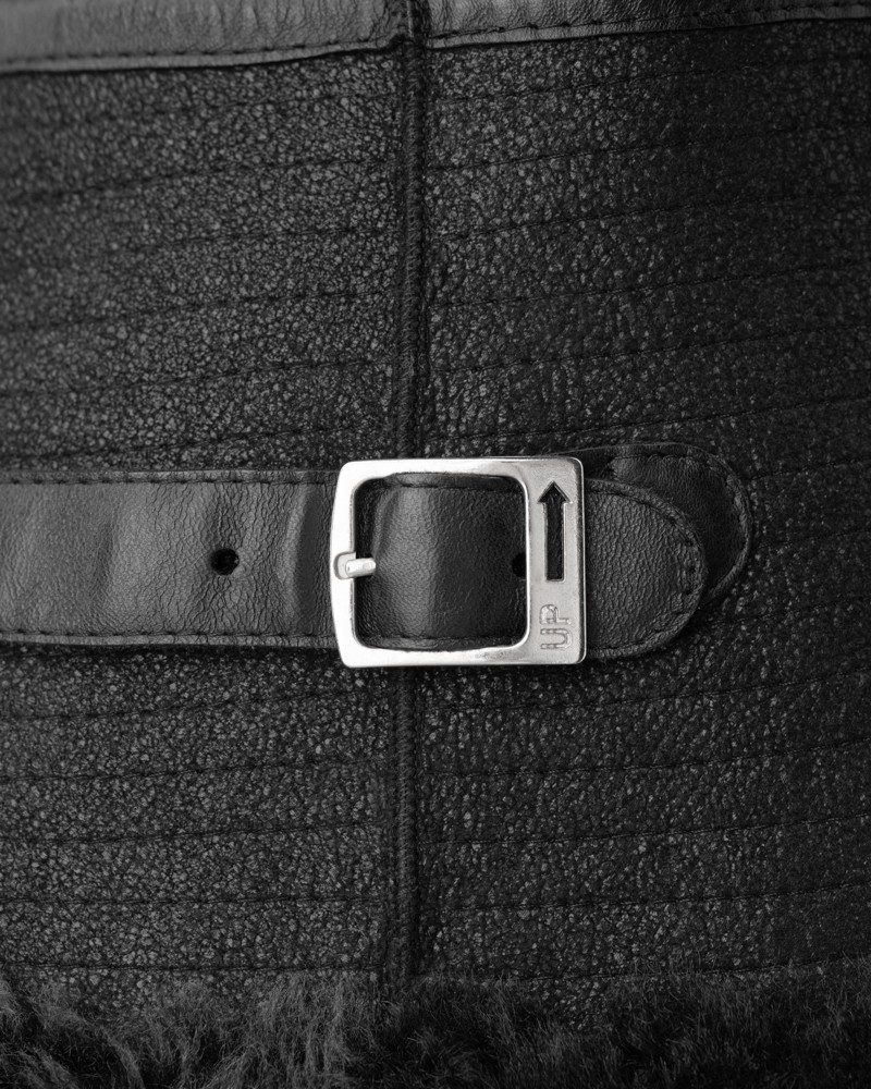 Czarny kożuch damski z futrzanym wykończeniem, ozdobiony skórzanym paskiem z metalową klamrą