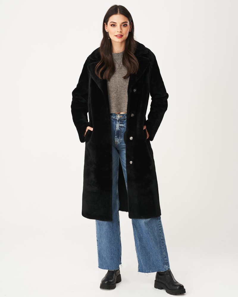Czarny kożuch damski z dużym kołnierzem, zapinany na guziki, z kieszeniami i długim krojem