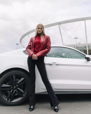 Kurtka skórzana damska w kolorze czerwonym z eleganckim krojem, zestawiona z czarnymi spodniami i wysokimi butami