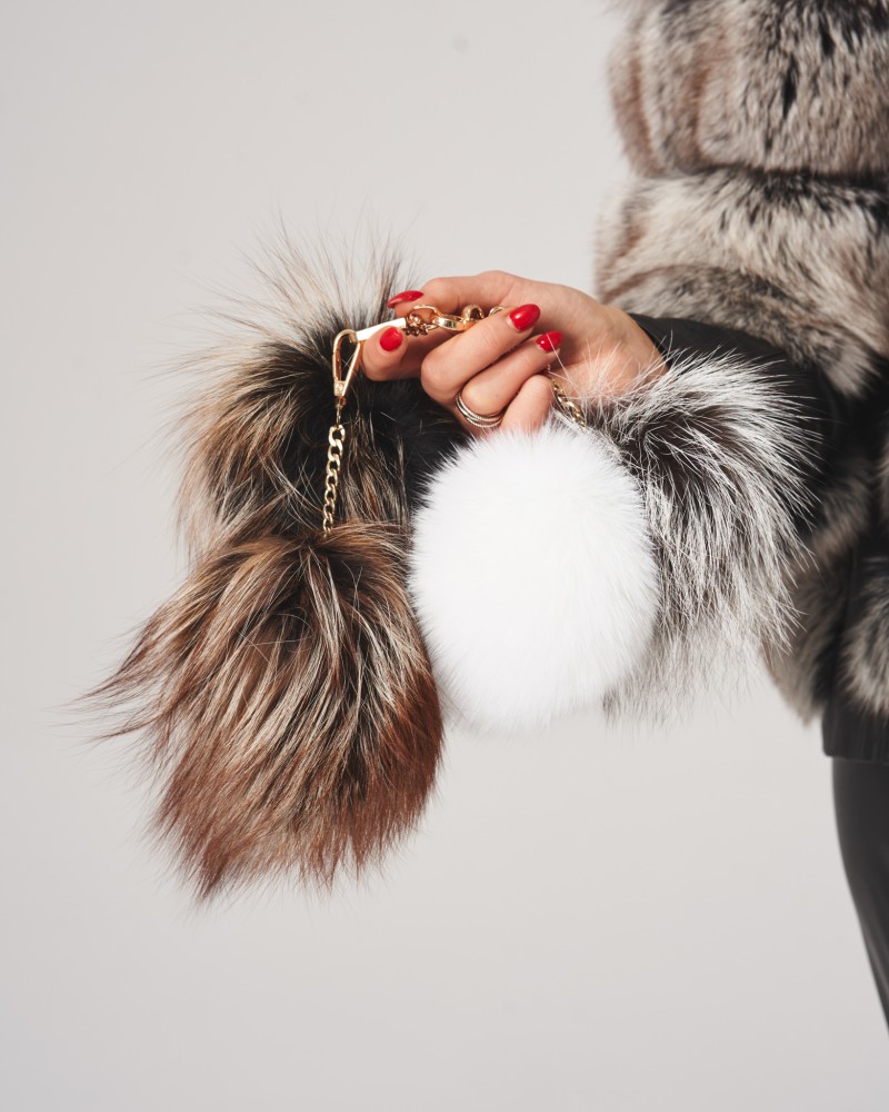 Futro naturalne w odcieniach brązu i bieli z efektownymi pomponami na złotym łańcuszku